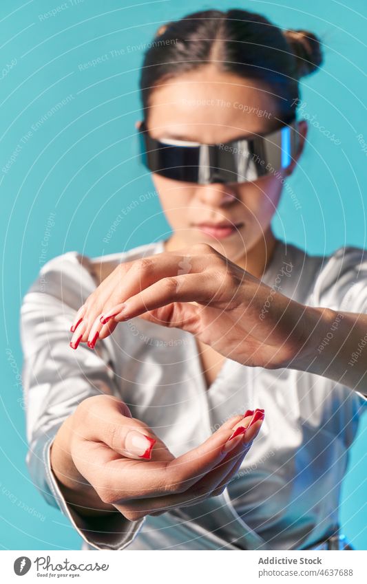 Junge ethnische Frau, die ein unsichtbares Objekt berührt, während sie in einem Studio die virtuelle Realität erlebt Erfahrung Virtuelle Realität Stil