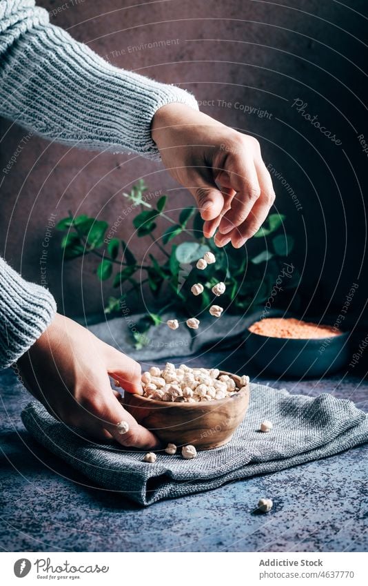 Anonyme Person schüttet Kichererbsen eingießen Hülsenfrüchtler kulinarisch Küche organisch Lebensmittel roh ungekocht Schalen & Schüsseln Hand Tisch Handtuch