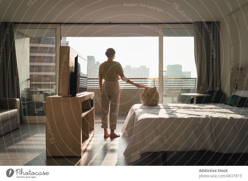 Junge Frau mit Tasche steht in der Nähe des Bettes in einem modernen Schlafzimmer Feiertag Hotel Urlaub Ausflug Windstille Tourist Unterkunft reisen jung lässig