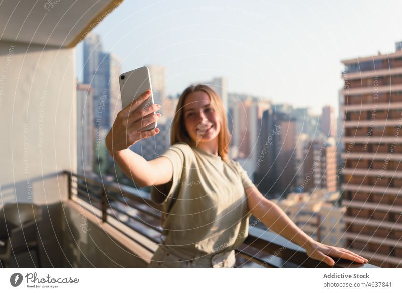 Glückliche Frau nimmt Selfie auf Balkon mit Blick auf die Stadt Smartphone Lächeln Terrasse Großstadt Gebäude positiv Reisender Feiertag Mobile Telefon