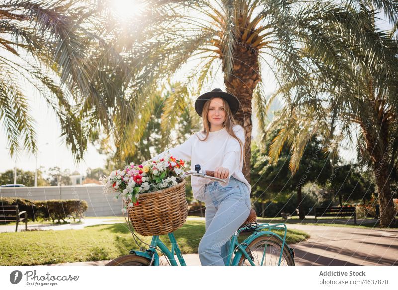 Junge Frau fährt Fahrrad im Park Mitfahrgelegenheit Weg Blume Wochenende tropisch Stil Sommer lässig Blumenstrauß jung exotisch frisch Blüte Gasse Fahrzeug