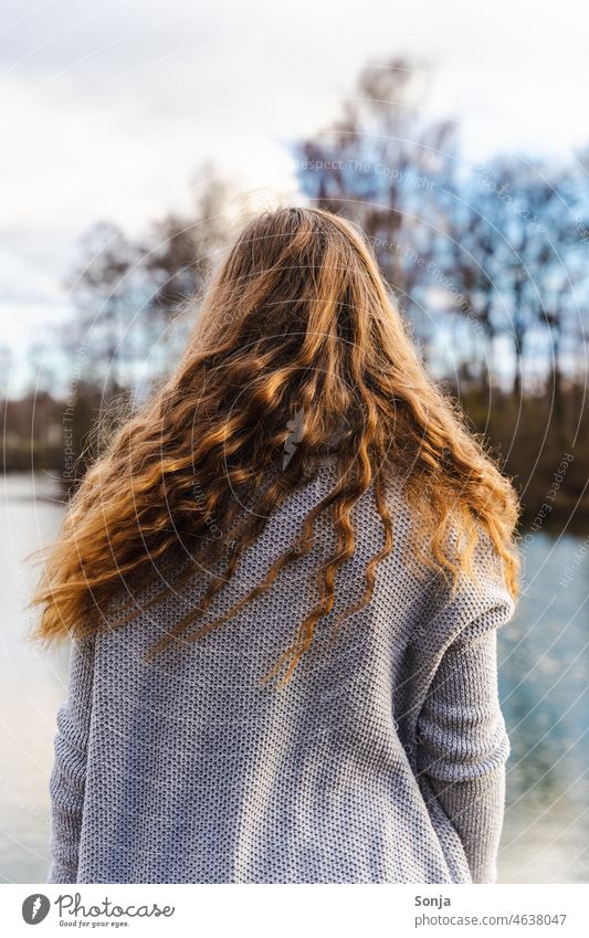 Rückansicht von einer jungen Frau mit langen gelockten Haaren langhaarig lockig brünett draußen Seeufer Winter schön feminin Erwachsene Haare & Frisuren Mensch