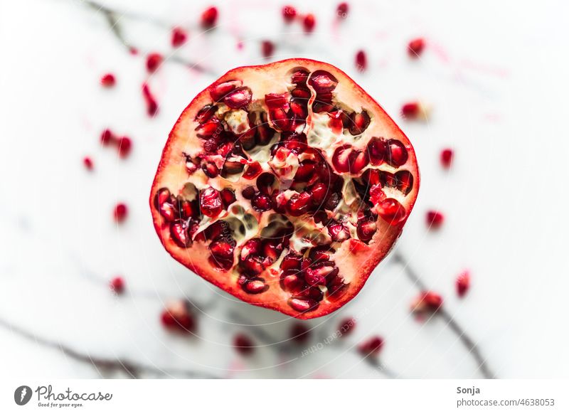 Draufsicht auf einen halbierten Granatapfel auf einen marmorierten Hintergrund. Querschnitt reif roh rot Frucht organisch Lebensmittel Gesundheit Vitamin