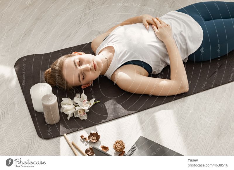 Junge schöne sportliche blonde Mädchen ist in Hatha-Yoga in einem modernen hellen Studio beschäftigt. Sie liegt auf dem Boden und meditiert mit geschlossenen Augen. Nahaufnahme