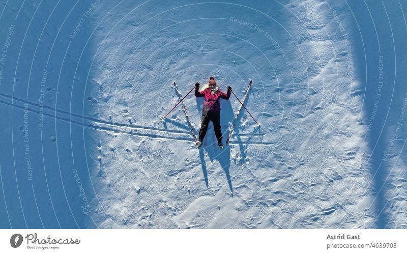 Luftaufnahme mit einer Drohne von einer Frau mit Langlaufski im Schnee. Wintersport für Senioren luftaufnahme drohnenfoto Seniorin Sport Schafe Skilanglauf
