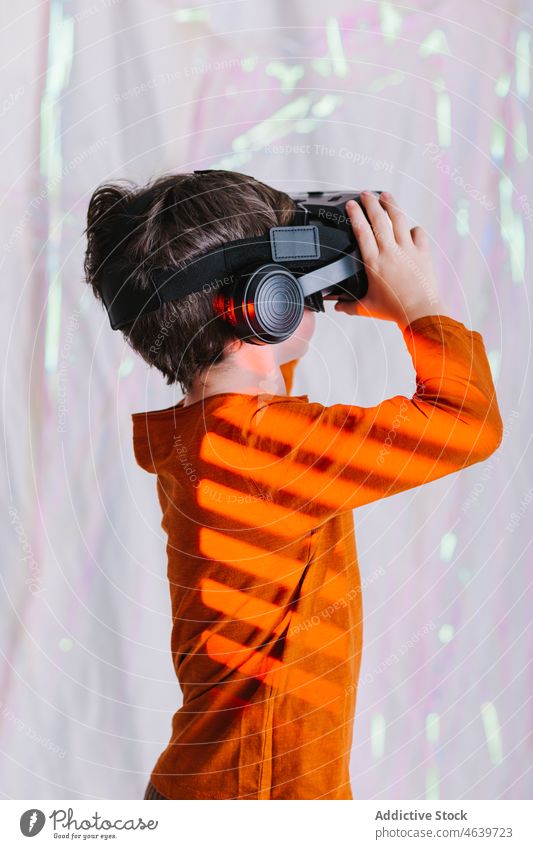 Junge erkundet den Cyberspace mit VR-Brille Kind Virtuelle Realität erkunden Erfahrung Schutzbrille Headset virtuell neonfarbig Apparatur Gerät Innovation