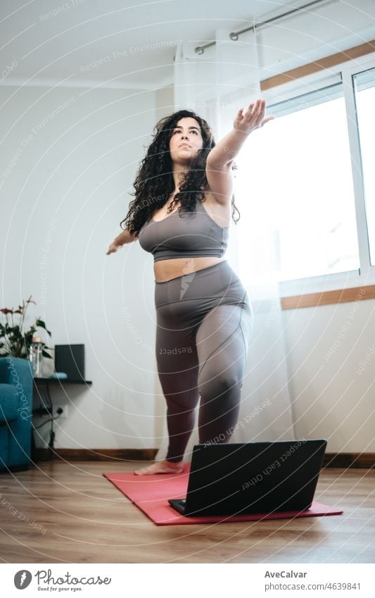 Ganzkörperaufnahme einer jungen Frau in Sportkleidung, die Yoga-Positionen auf dem Boden mit einem Laptop einnimmt. Raum kopieren. Abnehmen und Gesundheit zu Hause gewinnen. Online-Klasse mit dem Laptop-Konzept.