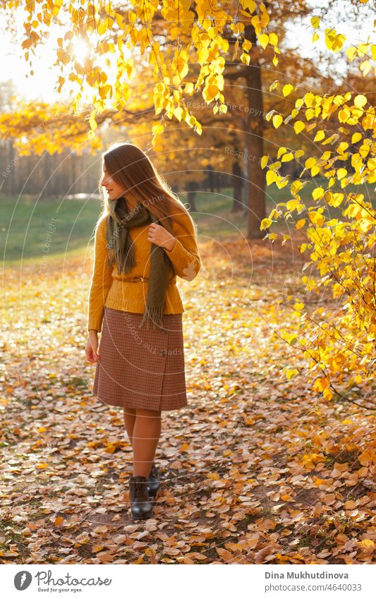 Schöne Frau in gelben Pullover im Herbst Park in der Nähe von Bäumen mit gelben Blättern bei Sonnenuntergang. Verbringen Sie Zeit in der Natur, um Frieden im Kopf, entspannende Momente und minfullness zu halten.  Herbst-Stil und Mode, lässige Kleidung.