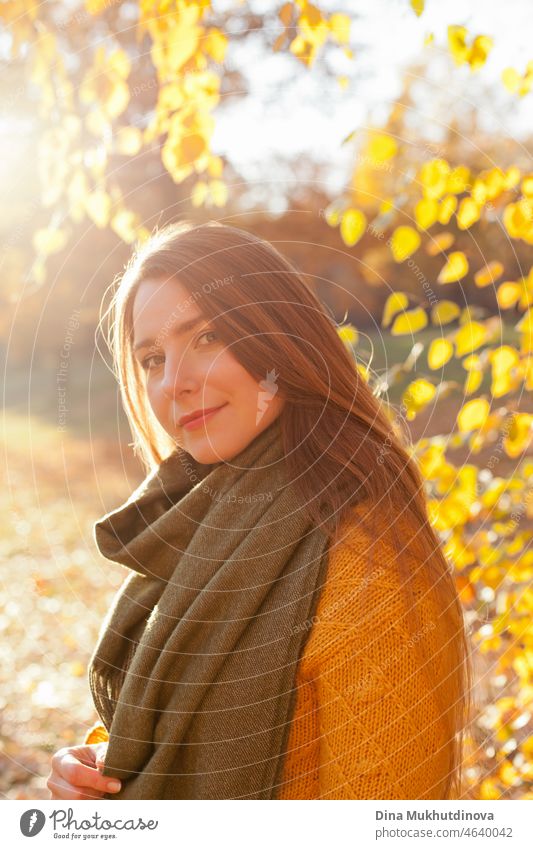 Schöne Frau in gelben Pullover und grünen Schal im Herbst Park in der Nähe von Bäumen mit gelben Blättern bei Sonnenuntergang. Verbringen Sie Zeit in der Natur, um Frieden im Kopf, entspannende Momente und minfullness zu halten.  Herbst-Stil und Mode, lässige Kleidung.