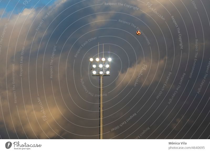 Beleuchtung eines Fußballplatzes mit Gewitterwolken im Hintergrund Scheinwerfer Lichter Stadion Fußballfeld Himmel blau Wolken Sport Unwetter Licht an Ballsport