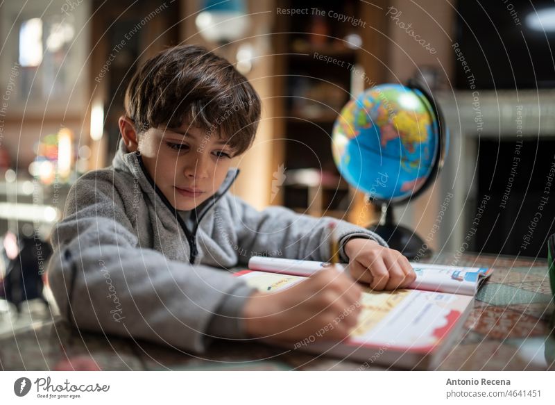 Kleiner Junge im Trainingsanzug macht zu Hause Hausaufgaben Kinder Hausarbeiten heimisch realistisch heimwärts Bücher Schüler Aktivität Menschen Kaukasier