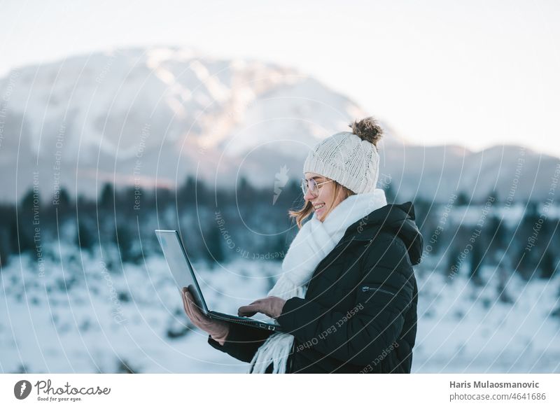 junge lächelnde Frau Freiberufler mit Laptop im Freien im Schnee Berge 5g Abenteuer schön kalt Mitteilung digitaler Nomade Wald Freiheit Spaß Mädchen Glück