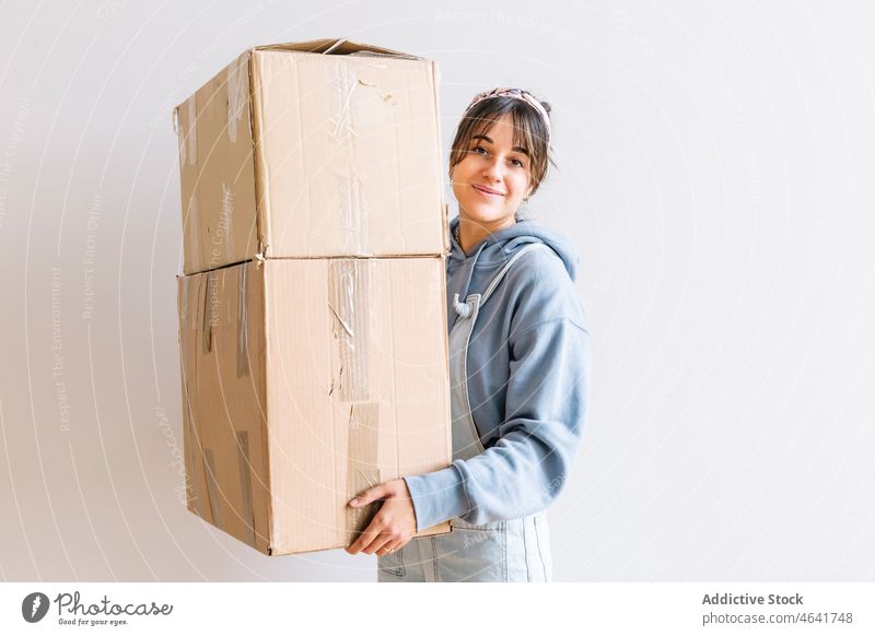 Positive Frau trägt Kartons Kasten führen verlegen Zugehörigkeit Lächeln Stapel Hypothek Hausbesitzerin positiv lässig Schachtel Optimist jung Paket einziehen