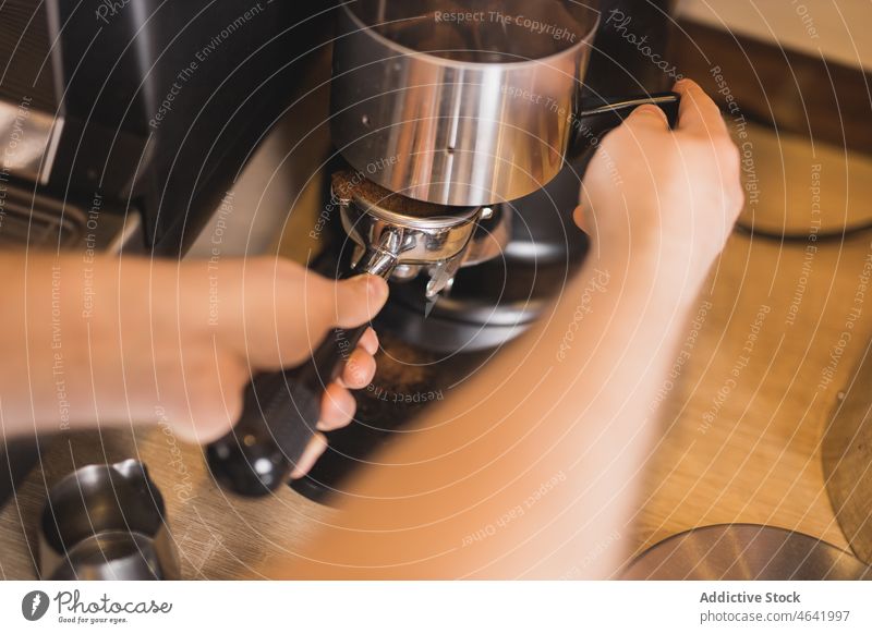 Barista beim Einsetzen des Siebträgers in die Edelstahl-Kaffeemühle Portafilter Schleifmaschine Boden frisch Maschine Vorrichtung Kaffeehaus vorbereiten