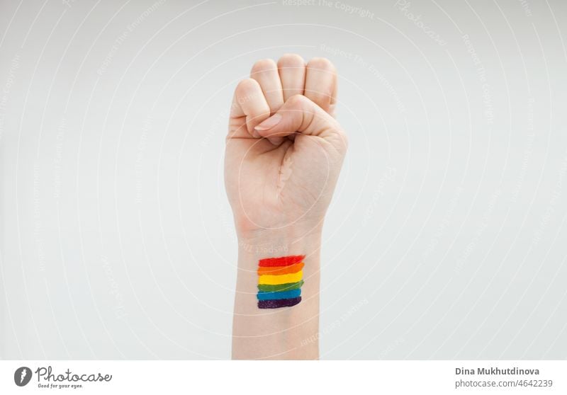 Erhobene Hand zur Unterstützung der Igbtq+-Gemeinschaft mit Regenbogenflagge auf dem Handgelenk - Aktivismus. Verbündete und Verbundenheit. Queer-LGT-Stolz. Symbol, Emblem, Zeichen auf der menschlichen Hand. friedlich, isoliert, Spektrum, Freiheit.