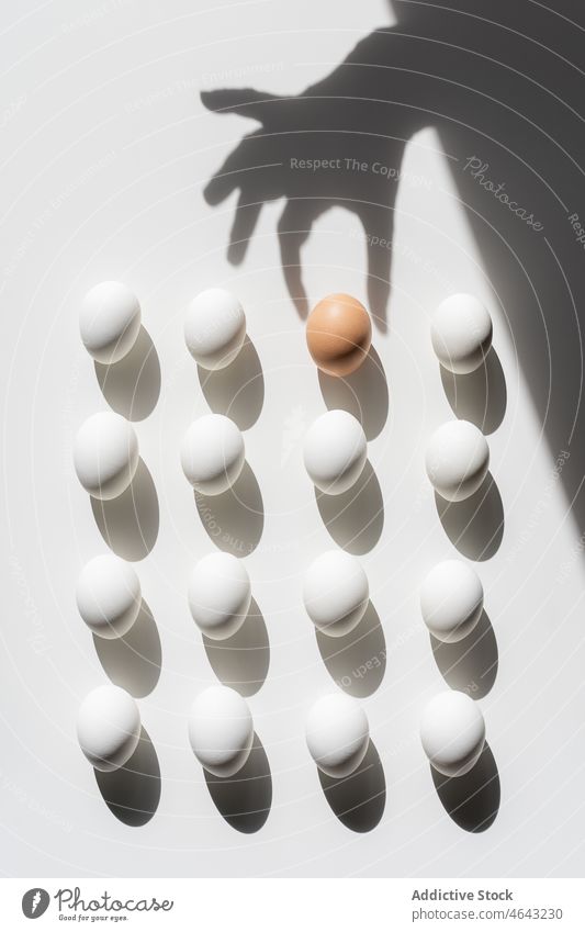 Ostern weiße Eier Muster auf einem weißen Hintergrund mit Schatten. Einer ist braun und unterscheidet sich von den anderen Menschengruppe Kugel dreidimensional