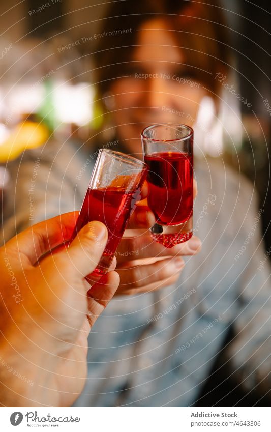 Anonymer Barkeeper stößt mit einer gesichtslosen Person auf Gläser mit Blut an Frau Getränk Alkohol Schuss Klirren Zuprosten jubelt Schnaps Arbeit Glas