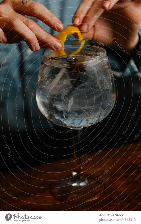Anonymer Barkeeper gibt Zitronenschale ins Glas Frau Gin Tonic Schale Zitrusfrüchte Arbeit trinken Frucht Getränk Eiswürfel Alkohol Schnaps kalt durchsichtig