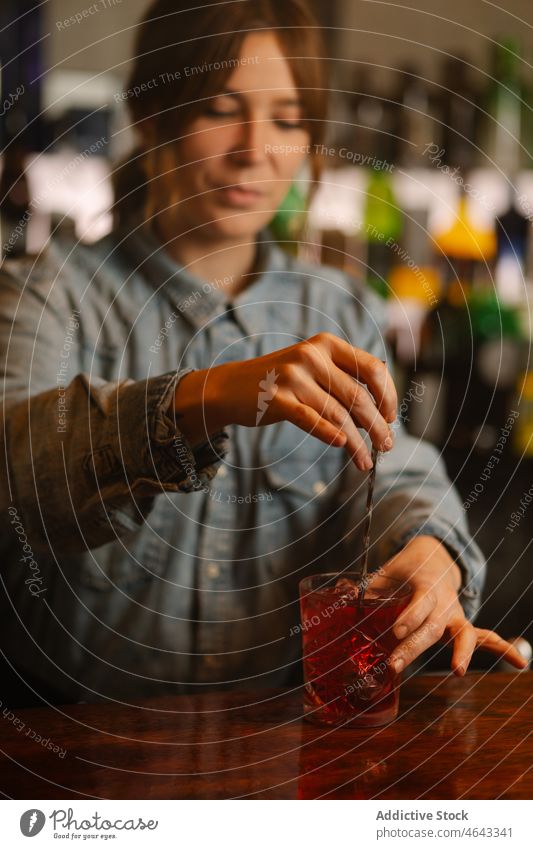 Barkeeper bei der Zubereitung eines Cocktails in einer Bar Frau altmodisch mischen Getränk Alkohol dienen Schnaps Arbeit Abfertigungsschalter Eiswürfel kalt
