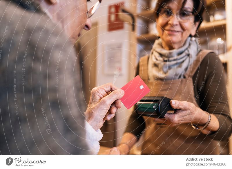 Anonyme ältere Frau benutzt Kreditkarte beim Bezahlen in einem Öko-Laden Frauen Zahlung Kunde Terminal positiv Senior Werkstatt Verkäufer Gewerbe