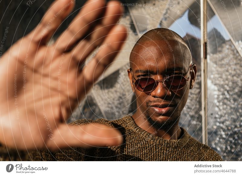 Schwarzer Mann schützt sich mit der Hand vor der Sonne Sonnenlicht sonnig Deckung Straße Gebäude Vorschein Stil Handfläche Sonnenbrille ernst männlich kahl