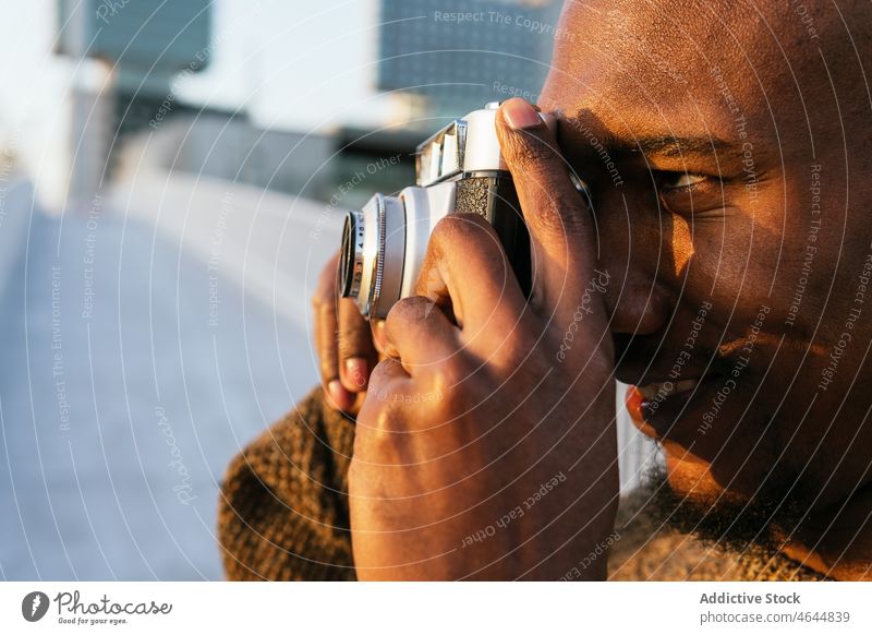 Lächelnder schwarzer Mann beim Fotografieren auf der Straße Fotoapparat fotografieren heiter Hobby einfangen Zeitvertreib Rasen Großstadt männlich kahl