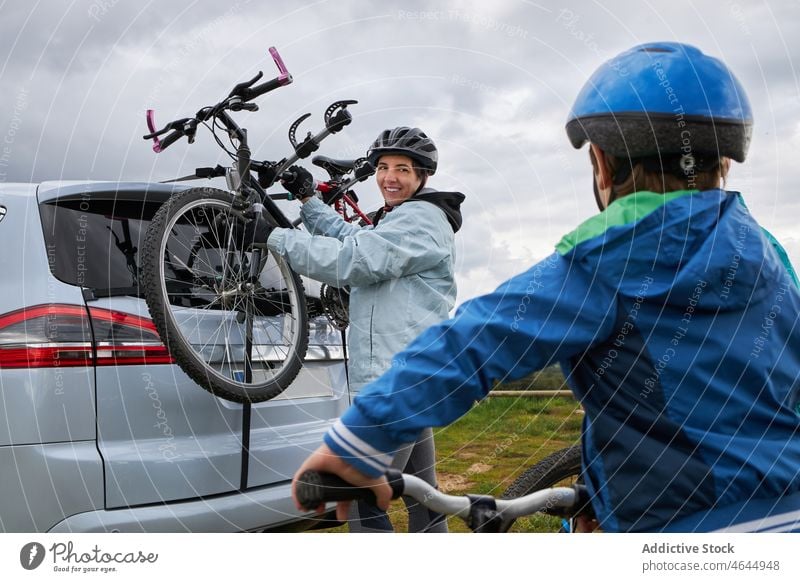 Frau mit Sohn nimmt Fahrrad aus dem Kofferraum eines Autos Mutter PKW Landschaft Ablage Hobby Aktivität Zeitvertreib Reise Autoreise Natur Junge Kind