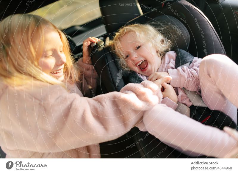 Schwestern spielen im modernen Auto Mädchen spielerisch Spaß haben PKW Autoreise Mitfahrgelegenheit Zeitvertreib Passagier Ausflug Automobil Arbeitsweg Sitz