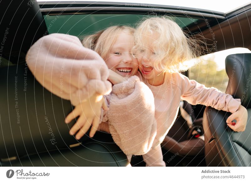 Positive Schwestern spielen im Auto Mädchen spielerisch Spaß haben PKW Autoreise Zeitvertreib Passagier Automobil Ausflug Arbeitsweg Fahrzeug Reise Kinder
