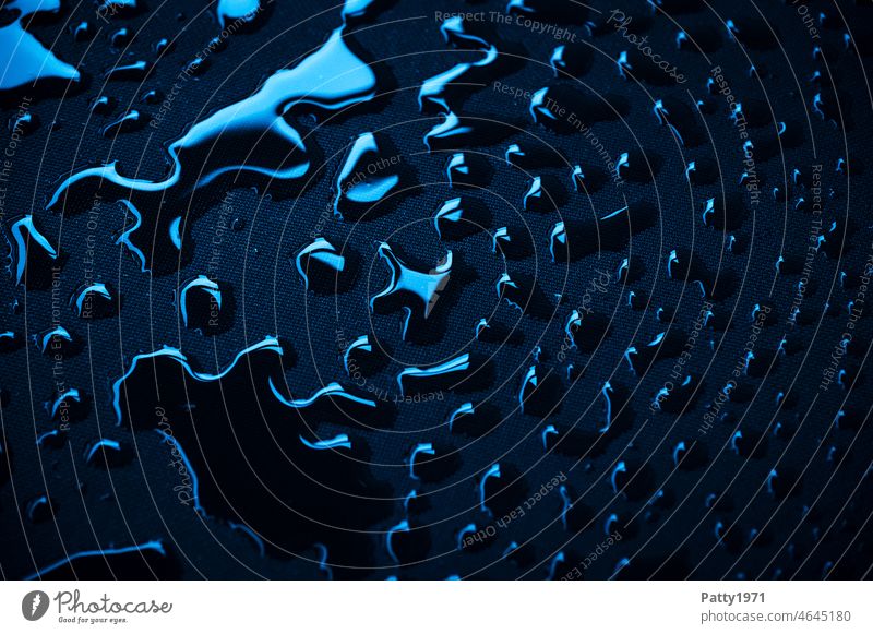Blaumetallisch glänzende Wassertropfen auf schwarzem Textil Untergrund blau Hintergrund abstrakt Textur Tropfen nass Oberfläche liquide Muster
