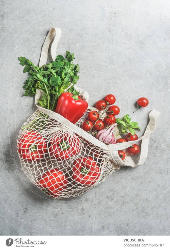 Verschiedene Gemüse und Kräuter in wiederverwendbarer plastikfreier Einkaufstasche verschiedene Küchenkräuter kunststofffrei grau Beton Tisch rot Paprika