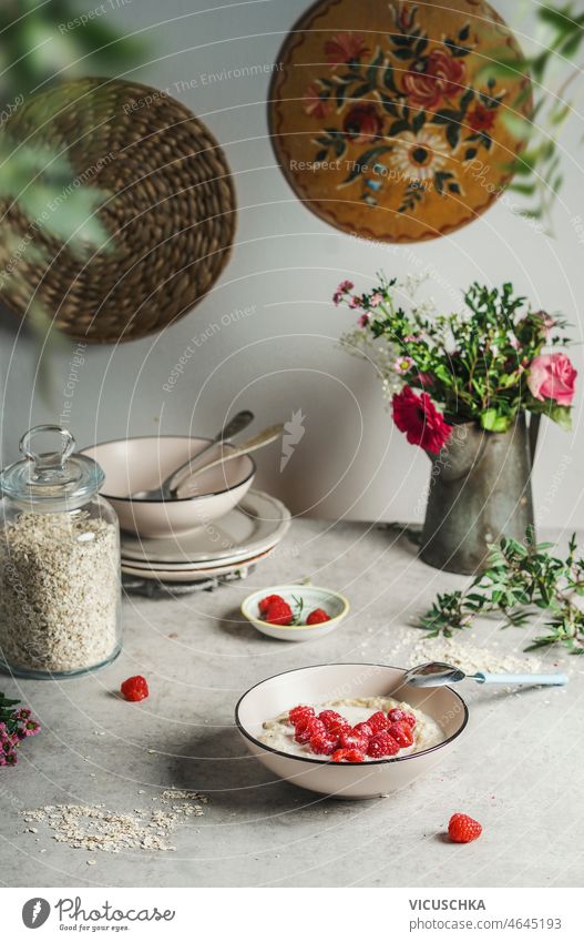 Schüssel mit Haferflockenbrei und Himbeeren Herz auf grauem Tisch mit Küchenutensilien Haferbrei Utensilien Blume Haufen geheftet Schüsseln Gesundheit