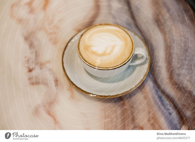 Eine Tasse Cappuccino auf einem marmorierten Tisch zu Hause oder in einem Café bei gemütlicher, warmer Beleuchtung Koffein Murmel Schreibtisch liquide