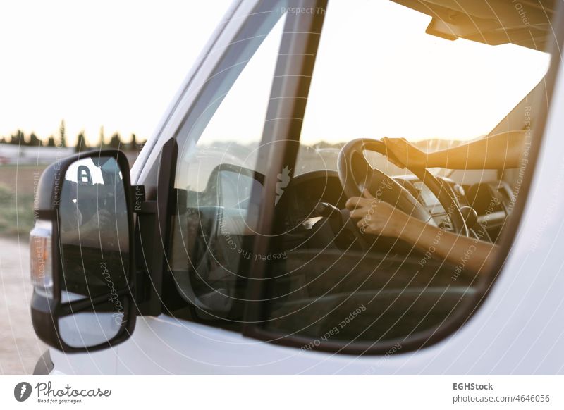 Blick von außen auf das Lenkrad eines Lieferwagens und die Hände einer Frau bei Sonnenuntergang, bevor die Fahrt beginnt fahren Abenteuer Airbag Atmosphäre Auto