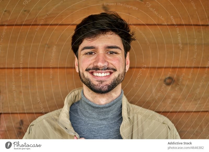 Bärtiger Mann in Oberbekleidung in der Nähe einer Holzwand Porträt Individualität Vorschein Starrer Blick cool selbstbewusst Persönlichkeit männlich Vollbart