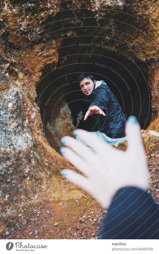 Junger Mann steigt in eine dunkle Höhle ein Abenteuer erkunden Speläologie Höhlenforschung Rücken im Inneren Mut Abenteurer allein einsam Einsamkeit