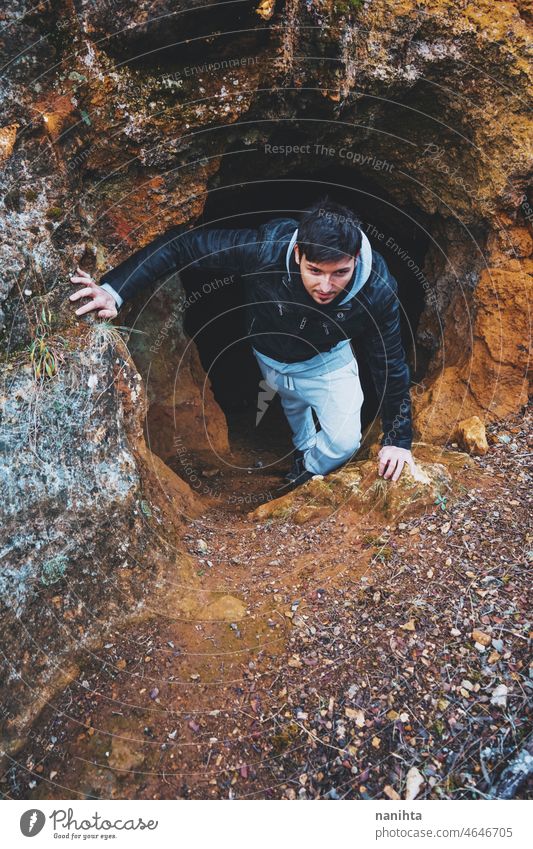 Junger Mann steigt in eine dunkle Höhle ein Abenteuer erkunden Speläologie Höhlenforschung Rücken im Inneren Mut Abenteurer allein einsam Einsamkeit