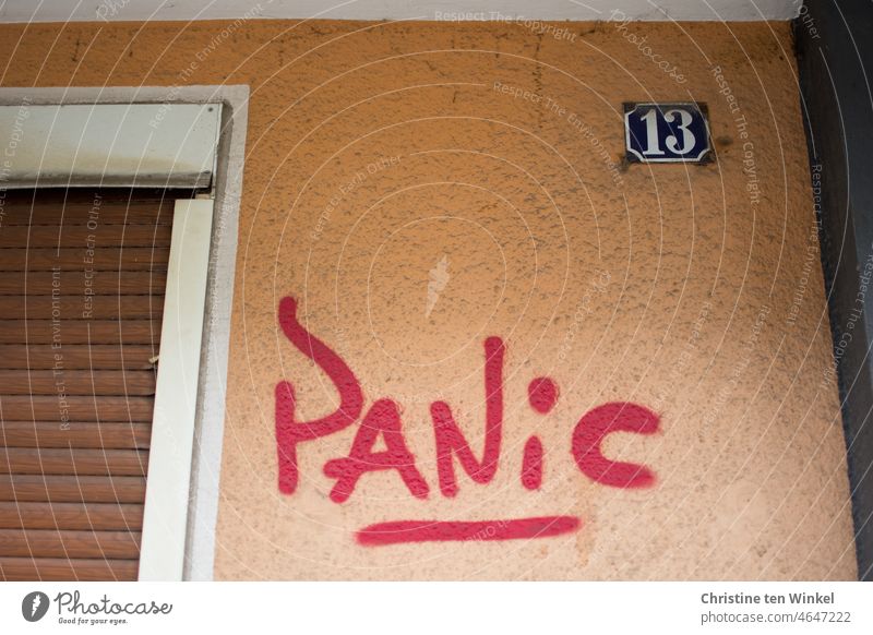 PANIC steht in roter Farbe auf der orange gestrichenen Fassade des Hauses mit der Nummer 13 Panic Panik Graffito Hauswand Hausnummer 13 Ziffern & Zahlen