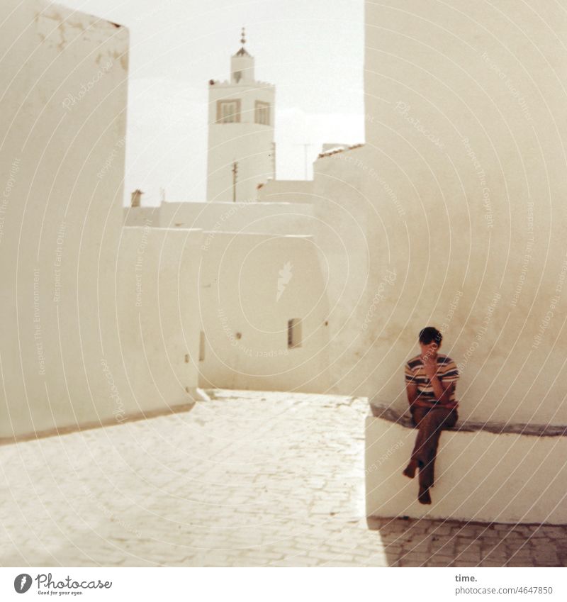 Schattenplatz mann sitzen urban architektur tunesien turm wand haus mauer straße innenstadt schatten sonnig hitze heiß hell sommer rauchen