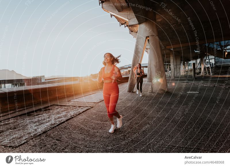 Zwei junge Mädchen joggen während eines Sonnenuntergangs, Hintergrundbeleuchtung, Zug auf ruban ambient Konzept. Working out Kleidung, Top und Leggings, afrikanische Frau Fitness. Sonnenuntergang ambient, schlanke Körper.