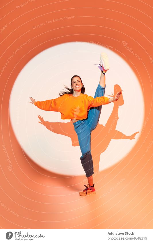 Glückliche Frau tanzt mit erhobenen Händen im Studio Tänzer sich[Akk] bewegen Lächeln Fähigkeit Probe Dehnung Projektor ausführen springen Energie dynamisch