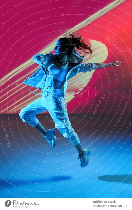 Frau tanzt mit erhobenen Händen in buntem Studio Tänzer sich[Akk] bewegen Fähigkeit Probe Dehnung springen Glück Projektor ausführen Energie dynamisch üben