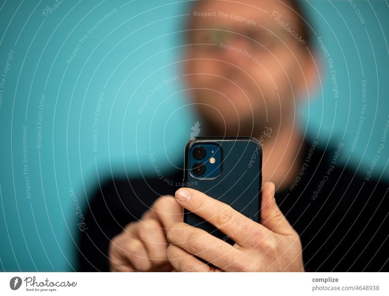 Ein Mann der mit Smartphone tippt & fotografiert Handy kamera Handykamera Fotografie Tippen Technologie smart Technik Sicherheit Passwortsicherheit eingeben