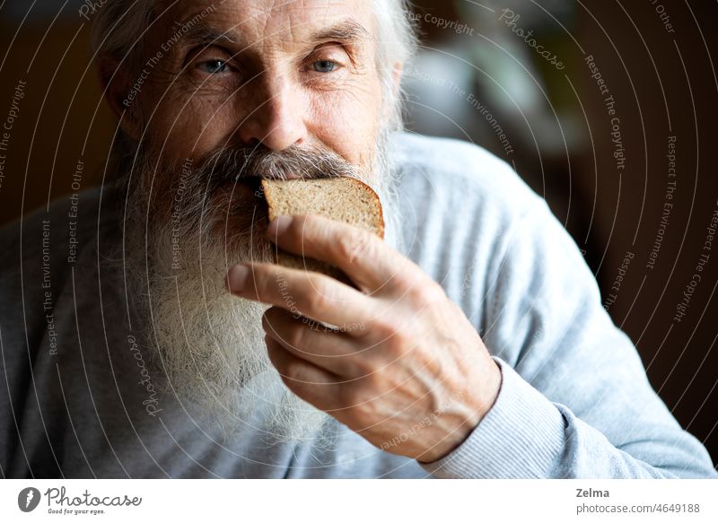 Alter trauriger Mann mit langem grauen Bart sitzt am Tisch und isst Suppe und Brot alt Senior älter Essen Beteiligung gezüchtet Nahaufnahme Gesicht Falte Auge