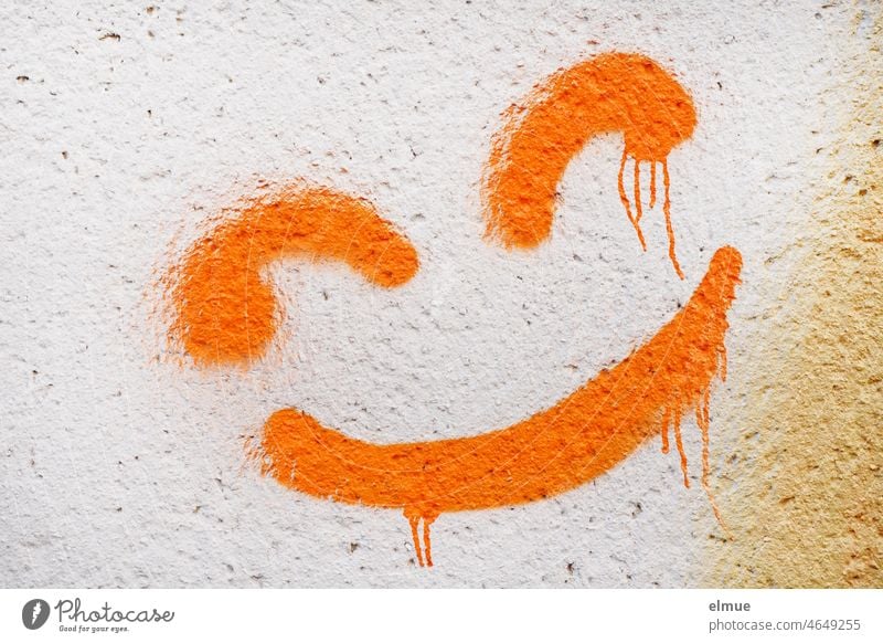 zerfließende orange Farbe eines an die Wand gesprayten Smileys / Jugendkultur / Optimismus Graffiti lachen schmunzeln Knallfarbe sprayen lächeln Freude positiv