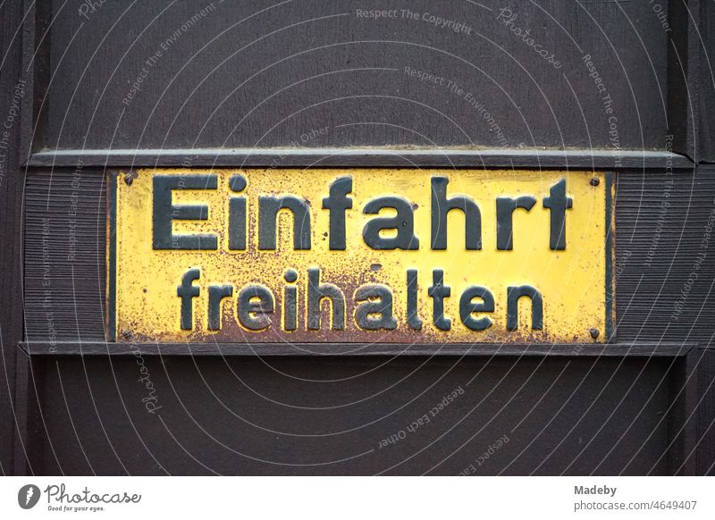 Rostiges gelbes altes Blechschild "Einfahrt freihalten" auf einem braunen Holztor in der Seckbacher Landstraße im Stadtteil Bornheim in Frankfurt am Main in Hessen