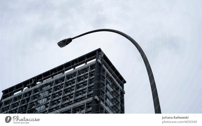 Ecke eines Hochhauses und Laterne - Architekturfotografie geometrisch Hauptstadt Linien groß trist urban Stadt grau Gedeckte Farben Himmel Außenaufnahme