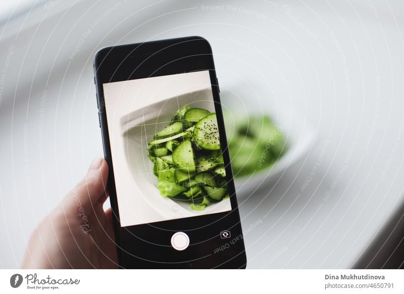 Holding Handy in der Nähe von Teller mit grünem Salat - Technologie Mock up für gesunde Ernährung Lebensstil. Mock up von Handy und gesundes Essen, Kalorienzählen und gesund essen. Essstörung Behandlung Therapie.