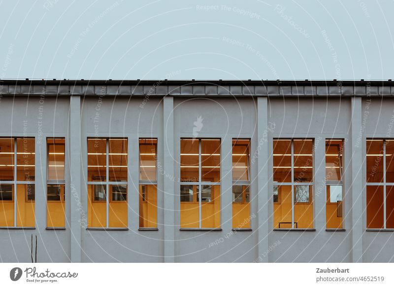 Blick auf eine Turnhalle mit erleuchteten Fenstern Licht Fassade Gebäude Struktur Architektur urban abstrakt geometrisch Muster Reihen