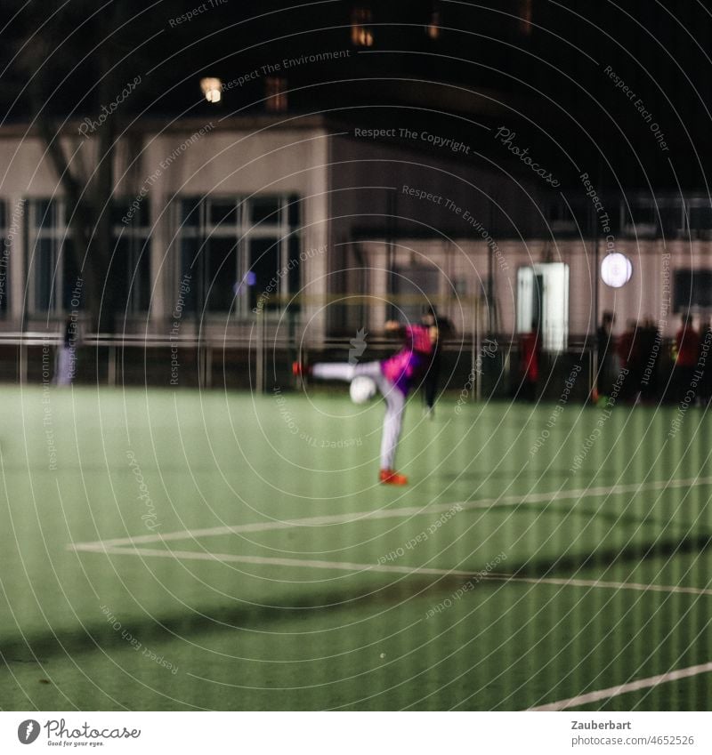 Fußballspieler beim Torschuss, schemenhaft bei Nacht auf erleuchtetem Sportplatz durch Zaun Ball Torschuß Bewegung Fußballplatz Flutlicht Strafraum Rasen grün